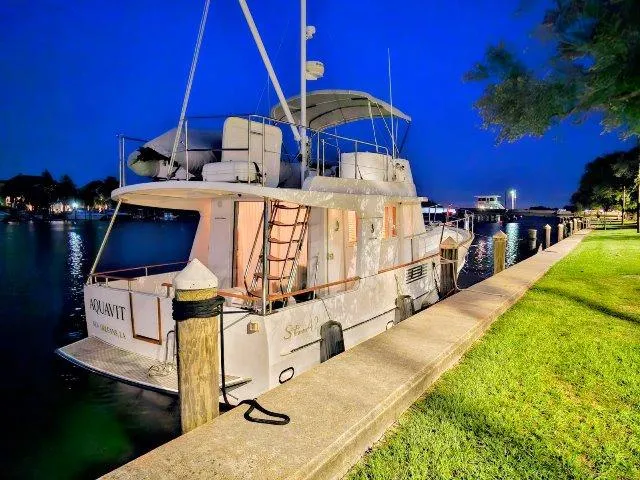 Slide: The Image of 2006 Beneteau Swift Trawler 42 docked at night, illuminated against a serene waterfront backdrop. - 6