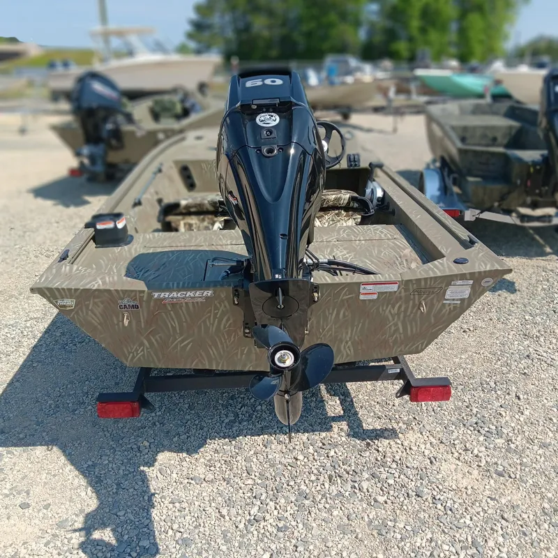 Slide: The Image of 2025 Tracker Grizzly 1754 SC boat with outboard motor, parked on gravel. - 3