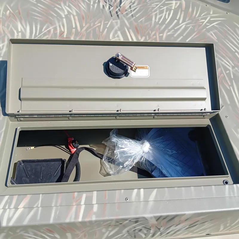 Slide: The Image of Open storage compartment of 2025 Tracker Grizzly 1754 SC boat with various items inside. - 5