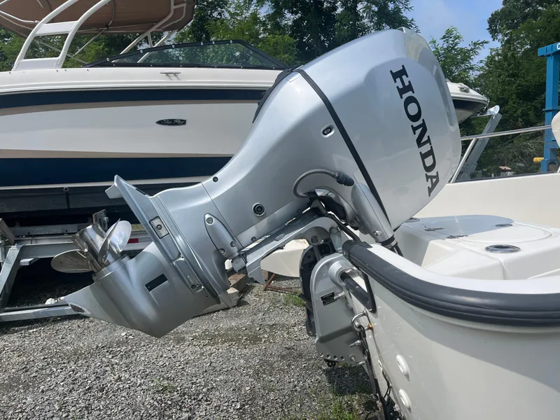 Slide: The Image of 2008 Boston Whaler 170 Montauk with Honda outboard motor, parked on gravel. - 22