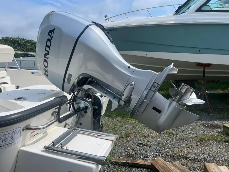 Slide: The Image of 2008 Boston Whaler 170 Montauk with Honda outboard motor, docked on gravel. - 24