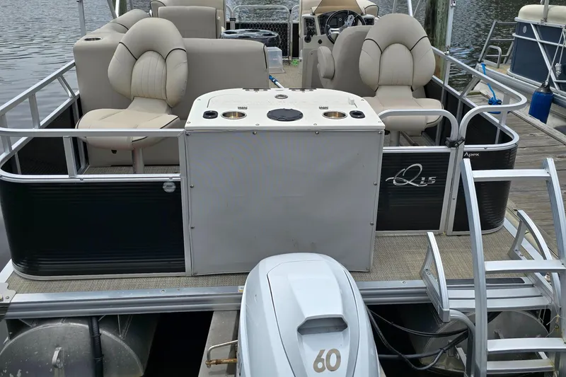 Slide: The Image of 2019 Qwest LS 818 RLS pontoon boat with seating and outboard motor, docked by the water. - 4