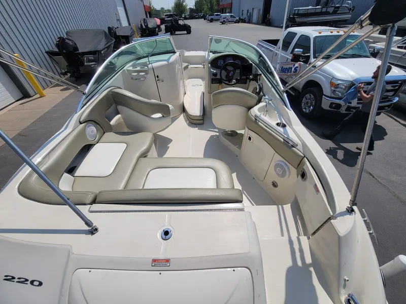 Slide: The Image of 2006 Sea Ray 220 Sundeck boat interior with seating and steering wheel, parked near trucks. - 14