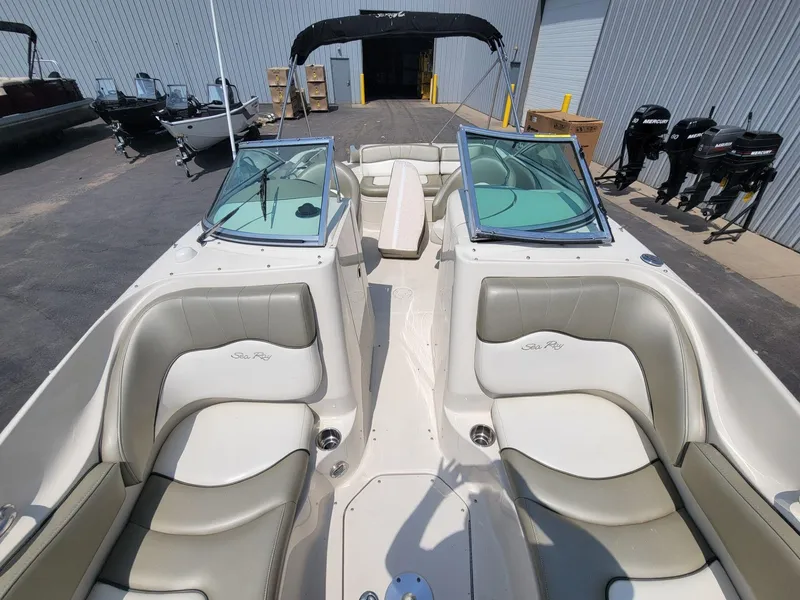 Slide: The Image of 2006 Sea Ray 220 Sundeck boat with beige seating and windshield, docked outdoors. - 27