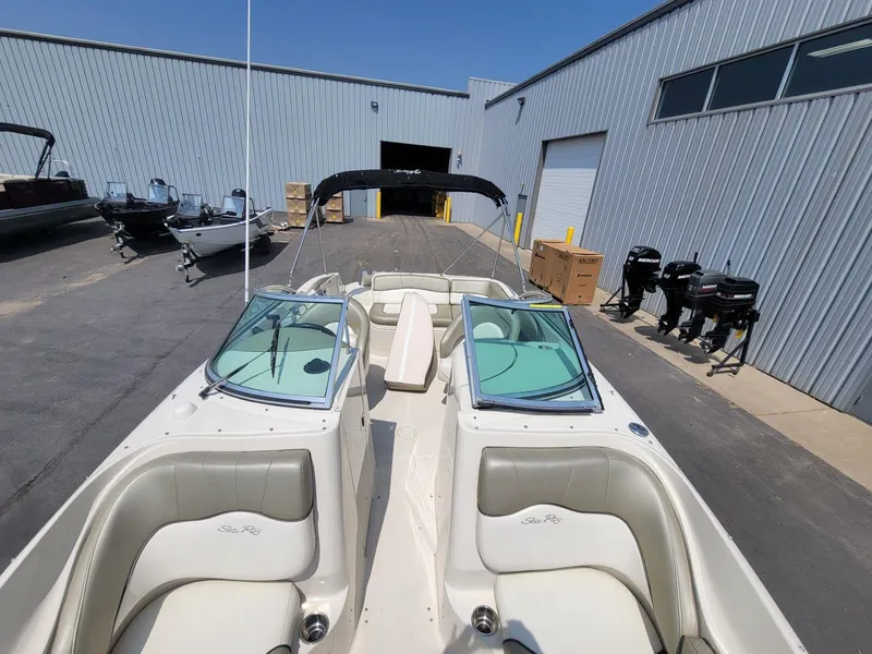 Slide: The Image of 2006 Sea Ray 220 Sundeck boat with open bow seating, parked near a warehouse. - 28