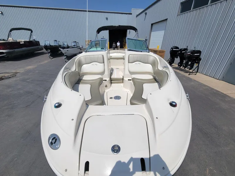 Slide: The Image of 2006 Sea Ray 220 Sundeck boat with spacious seating, parked near a metal building. - 29
