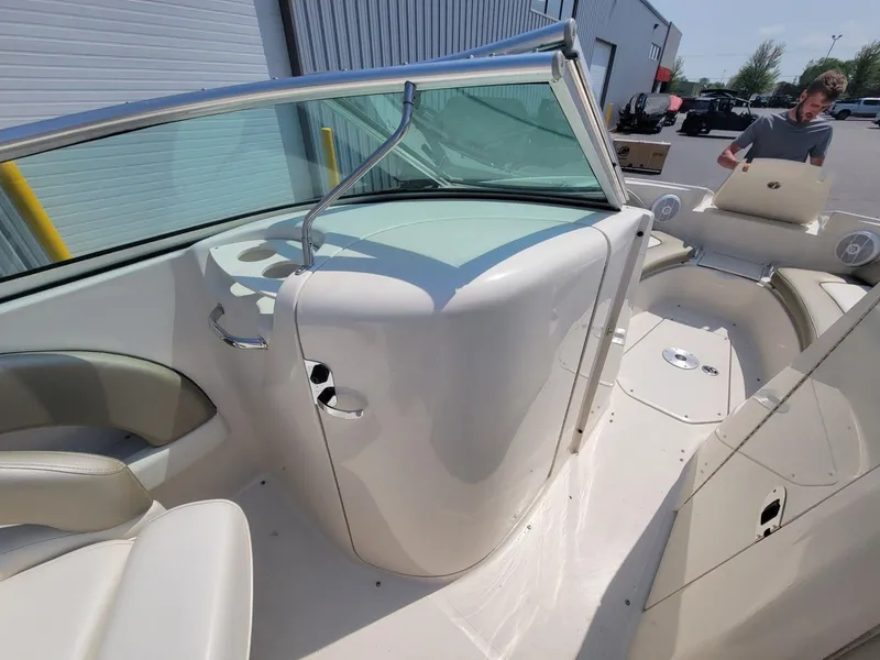 Slide: The Image of 2006 Sea Ray 220 Sundeck interior with seating and windshield, docked outdoors. - 30