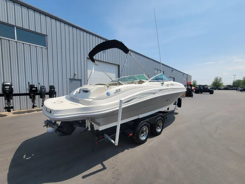 Slide: The Image of 2006 Sea Ray 220 Sundeck boat on trailer, parked outside a warehouse. - 6