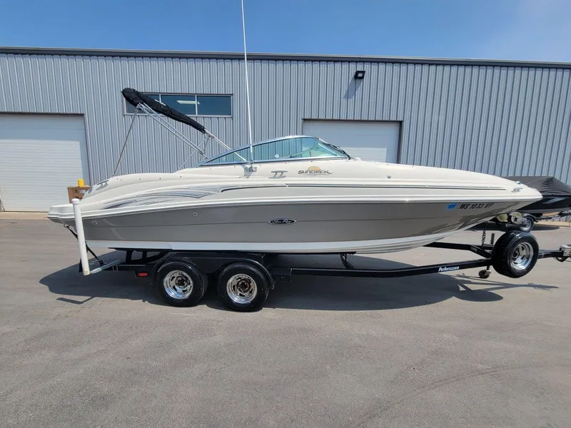 Slide: The Image of 2006 Sea Ray 220 Sundeck boat on trailer, parked outside industrial building. - 7