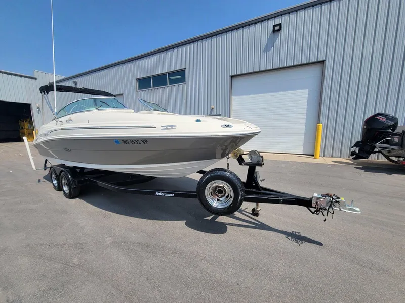 Slide: The Image of 2006 Sea Ray 220 Sundeck boat on trailer, parked outside industrial building. - 8