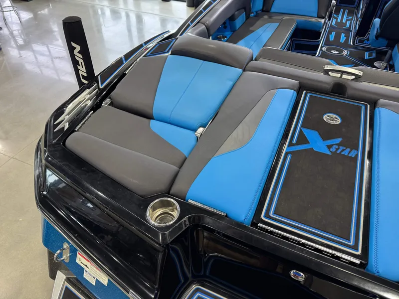 Slide: The Image of 2018 MasterCraft XStar boat interior with blue and gray seating, showcasing sleek design and branding. - 12