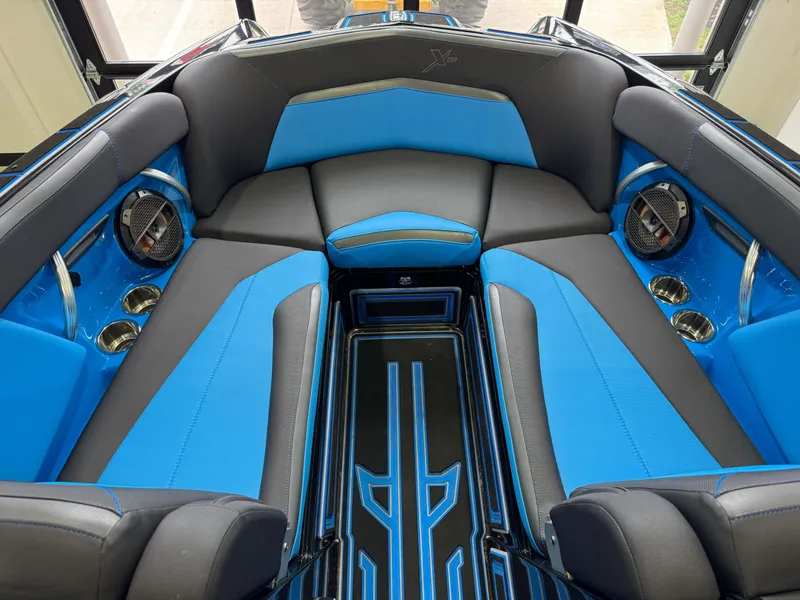 Slide: The Image of 2018 MasterCraft XStar interior with blue and black seating, featuring speakers and cup holders. - 17