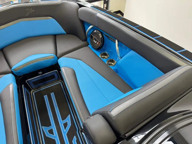 Slide: The Image of 2018 MasterCraft XStar interior with blue and black seating, cup holders, and speaker. - 18