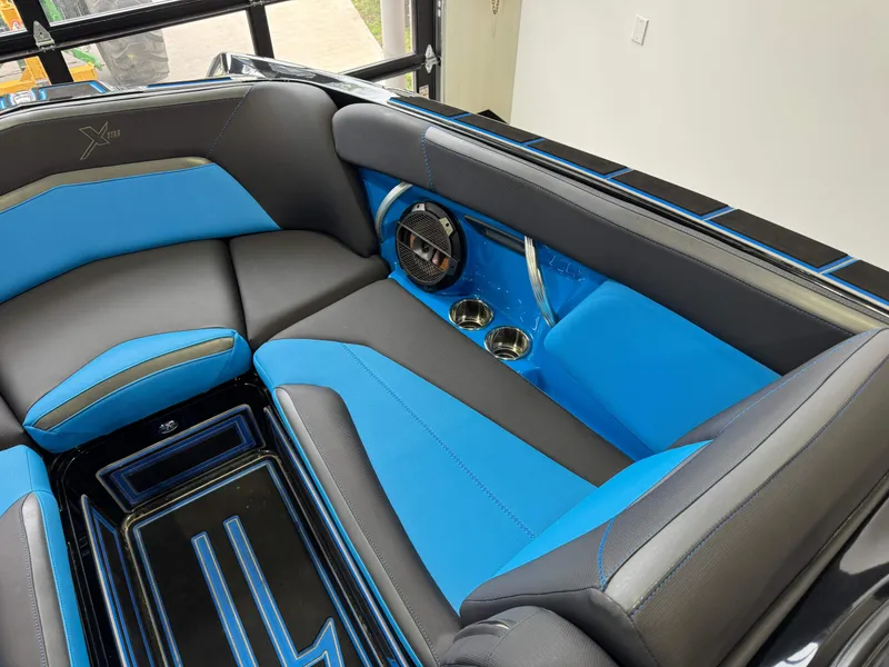 Slide: The Image of 2018 MasterCraft XStar interior with blue and black seating, cup holders, and speaker. - 21