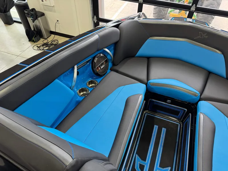 Slide: The Image of 2018 MasterCraft XStar interior with blue and black seating, cup holders, and speaker. - 22