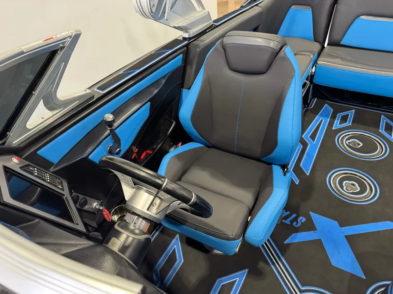 Slide: The Image of 2018 MasterCraft XStar interior with blue and black seating, steering wheel, and dashboard. - 24