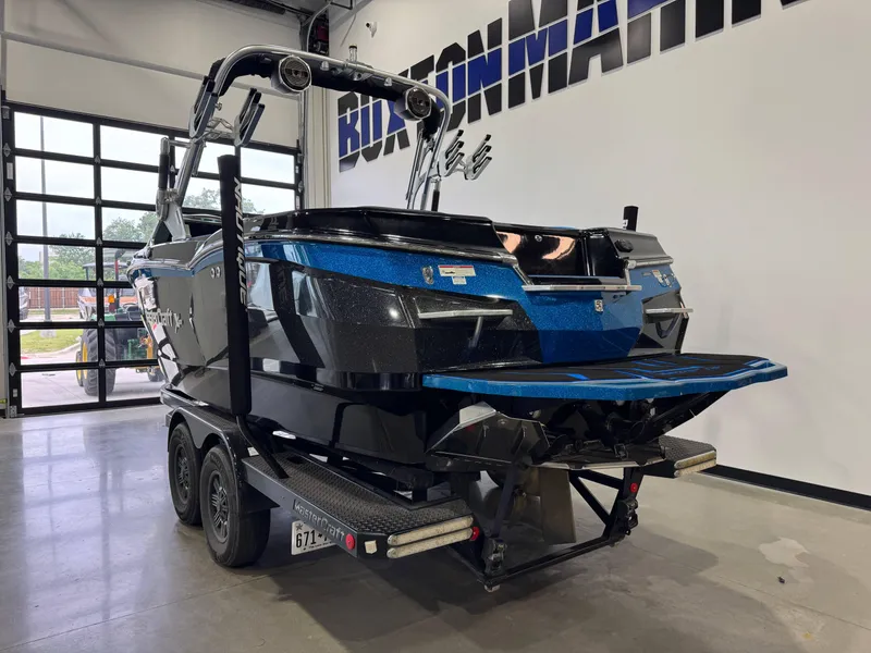 Slide: The Image of 2018 MasterCraft XStar boat on trailer in showroom, featuring sleek black and blue design. - 5