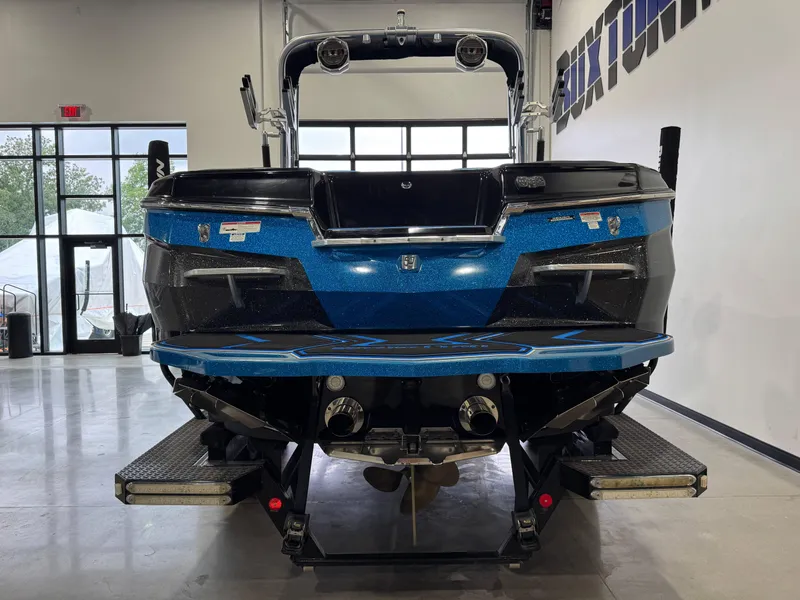 Slide: The Image of 2018 MasterCraft XStar boat in showroom, rear view, blue and black design. - 6