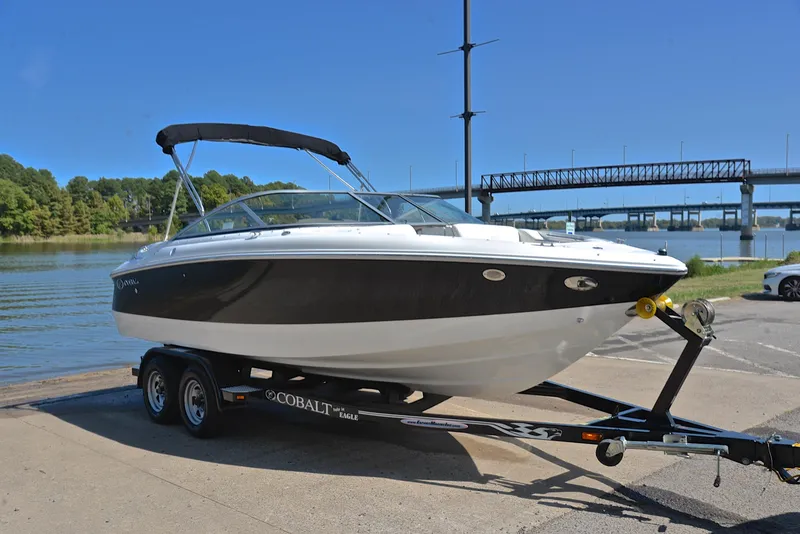 Slide: The Image of 2007 Cobalt 200 boat on trailer by a river, with a bridge in the background. - 16