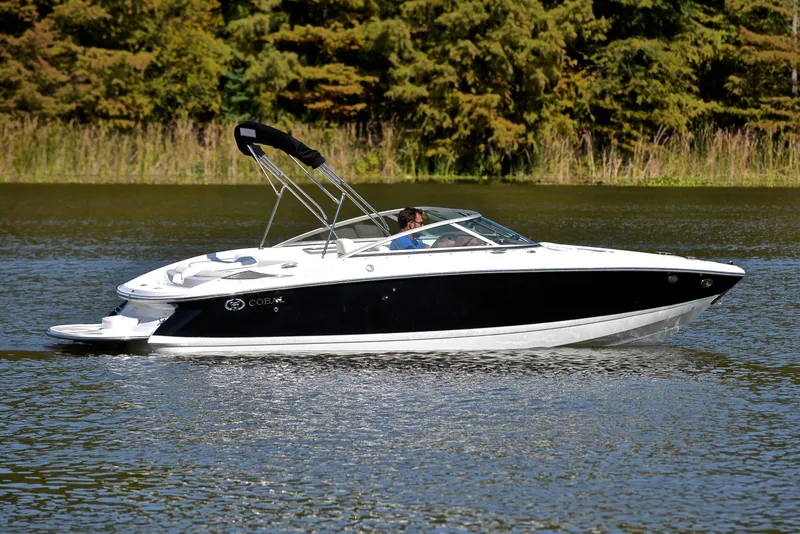 Slide: The Image of 2007 Cobalt 200 boat cruising on a serene lake with lush greenery. - 7