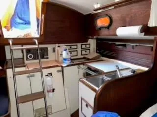 Slide: The Image of Interior of 1981 Cape Dory 33 Sloop, featuring compact kitchen and wooden cabinetry. - 16