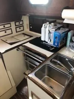 Slide: The Image of 1981 Cape Dory 33 Sloop kitchen with sink, stove, and storage cabinets. - 22