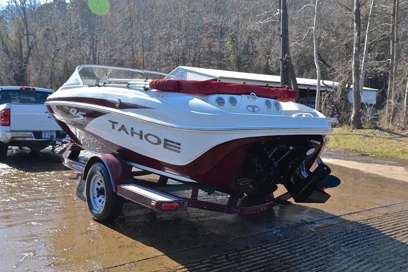 Slide: The Image of 2014 Tahoe Q5 boat on trailer, parked near a wooded area. - 12