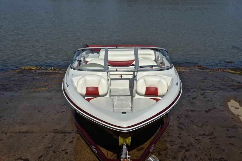 Slide: The Image of 2014 Tahoe Q5 boat on a ramp by the water, featuring white and red seating. - 17