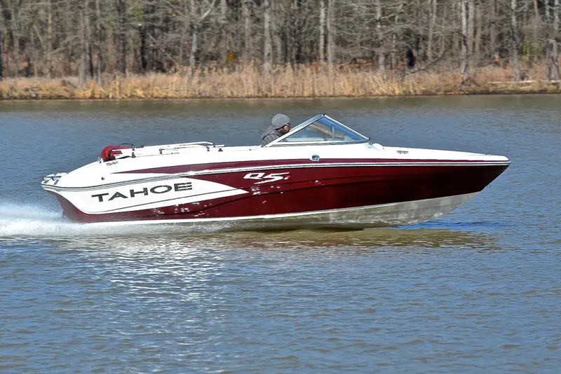 Slide: The Image of 2014 Tahoe Q5 boat cruising on a calm lake with forested background. - 3