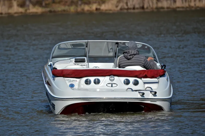 Slide: The Image of A 2014 Tahoe Q5 boat on a calm lake, with a person steering. - 8