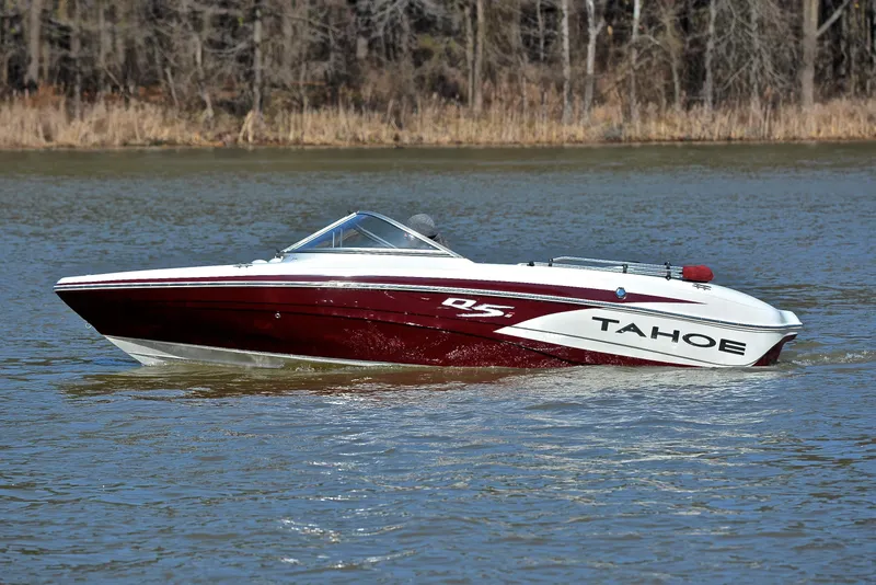 Slide: The Image of 2014 Tahoe Q5 boat cruising on a calm lake with wooded shoreline. - 9