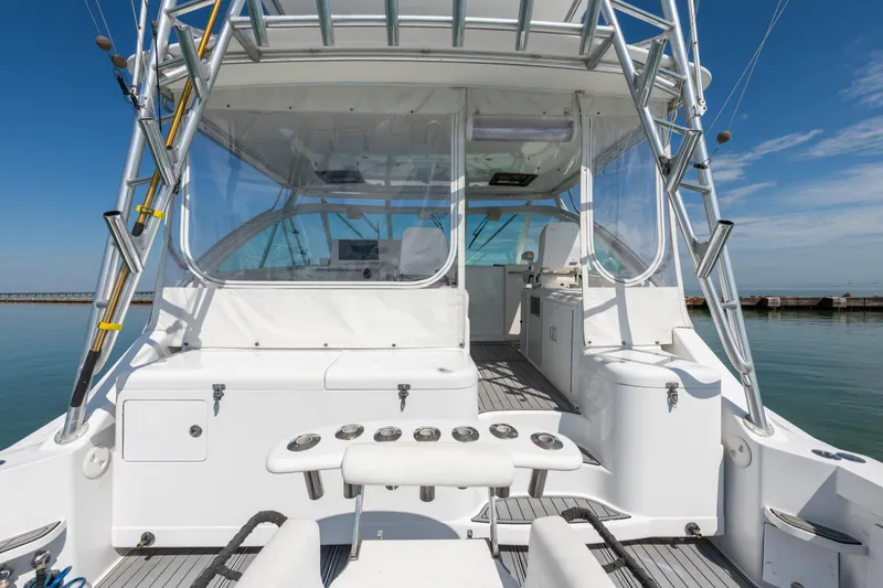 Slide: The Image of 2004 Cabo 40 Express yacht cockpit with fishing rod holders and clear enclosure. - 11