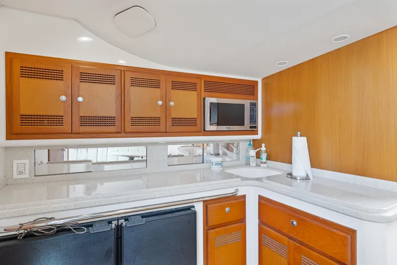 Slide: The Image of 2004 Cabo 40 Express yacht kitchen with wooden cabinets, microwave, and countertop. - 17