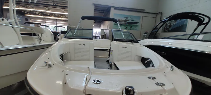 Slide: The Image of 2023 Sea Ray SPX 190 boat interior in showroom, featuring sleek white seating and modern design. - 11