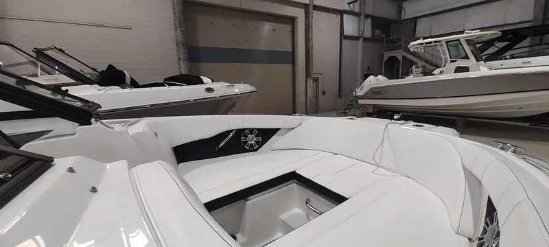 Slide: The Image of 2023 Sea Ray SPX 190 boat interior in showroom, featuring sleek white seating. - 19