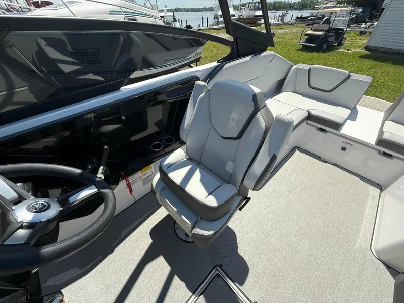 Slide: The Image of 2022 Yamaha Boats AR250 interior with sleek seating and steering wheel, docked by the water. - 10