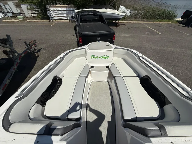 Slide: The Image of 2022 Yamaha Boats AR250 interior with white seating, parked near a truck. - 13