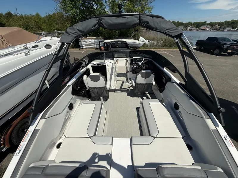 Slide: The Image of 2022 Yamaha Boats AR250 interior with seating and steering wheel, docked outdoors. - 8