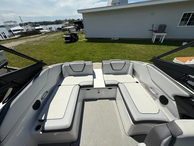 Slide: The Image of 2022 Yamaha Boats AR250 interior with spacious seating, docked near a waterfront. - 9