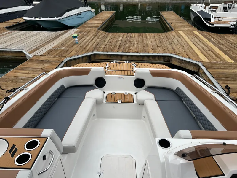 Slide: The Image of 2025 Starcraft SVX 211 OB boat interior with cushioned seating at a dock. - 11