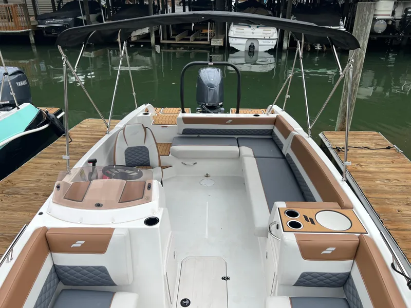 Slide: The Image of 2025 Starcraft SVX 211 OB boat with spacious seating and modern design at a dock. - 13