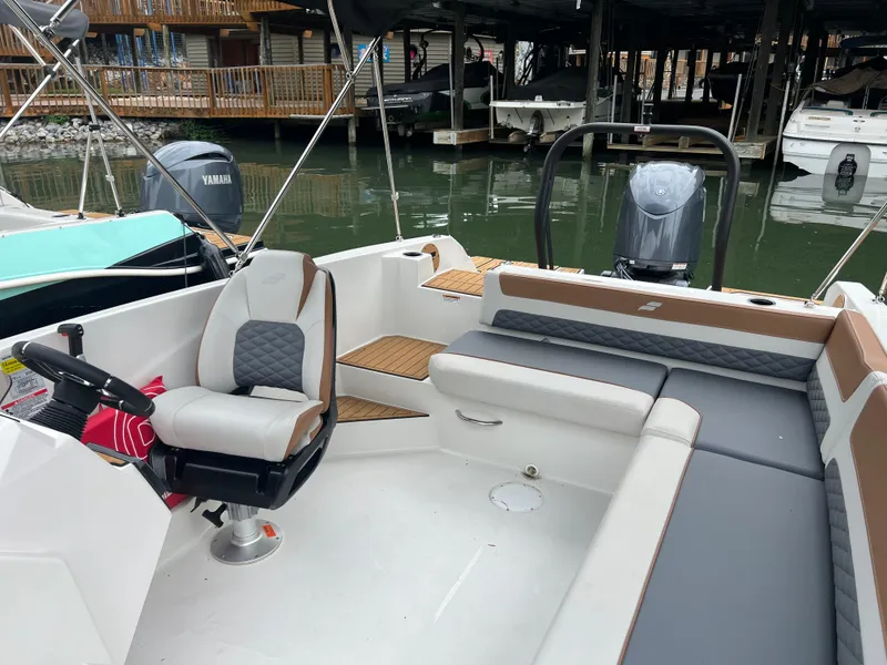 Slide: The Image of 2025 Starcraft SVX 211 OB boat interior with seating and steering, docked near other boats. - 14
