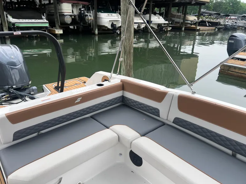 Slide: The Image of 2025 Starcraft SVX 211 OB boat interior with cushioned seating, docked near other boats. - 16