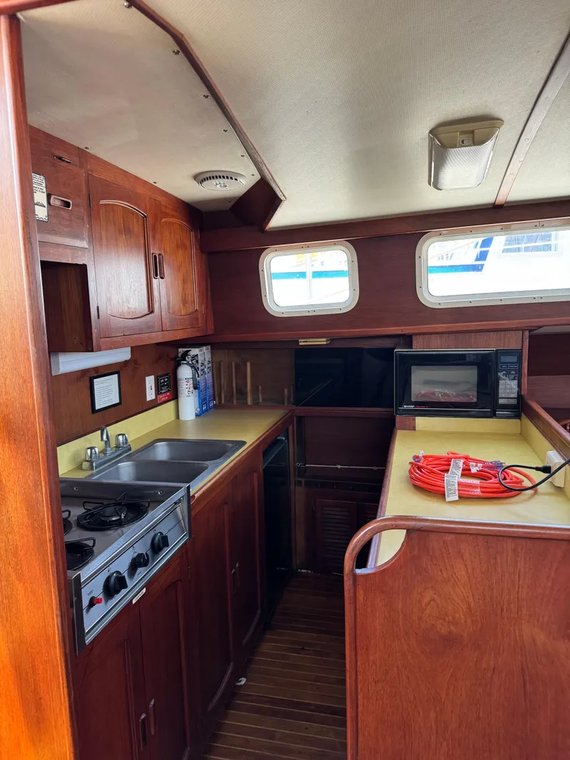 Slide: The Image of 1980 Cooper Marine Mapleleaf 48 yacht kitchen with wood cabinetry, stove, sink, and microwave. - 4