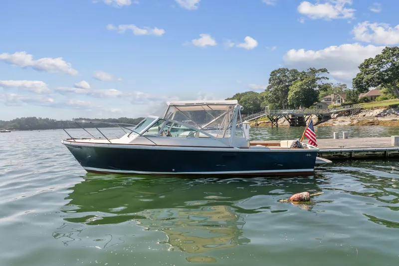 Slide: The Image of 2015 Hunt Yachts 25 Harrier docked by a scenic shoreline under a clear blue sky. - 12