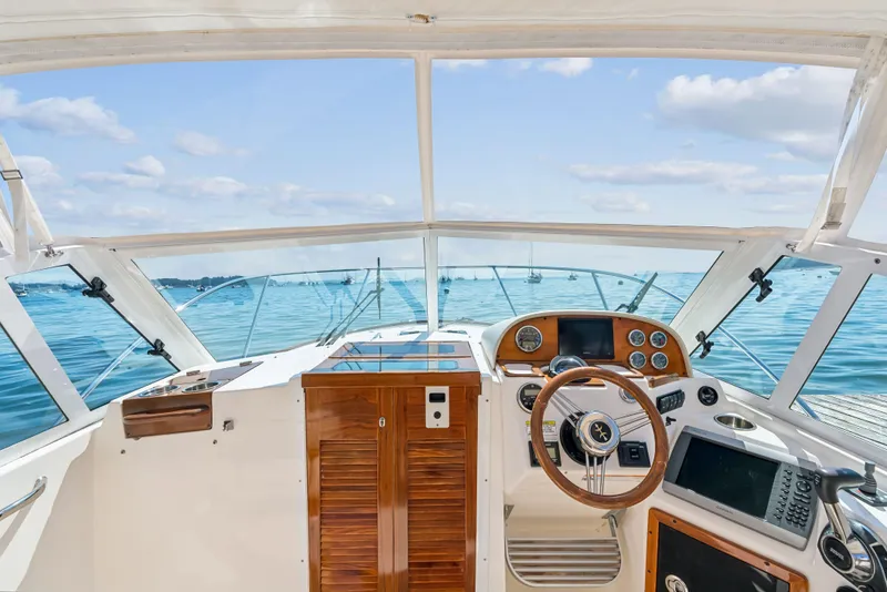 Slide: The Image of 2015 Hunt Yachts 25 Harrier helm with ocean view, featuring classic wooden dashboard and steering wheel. - 46