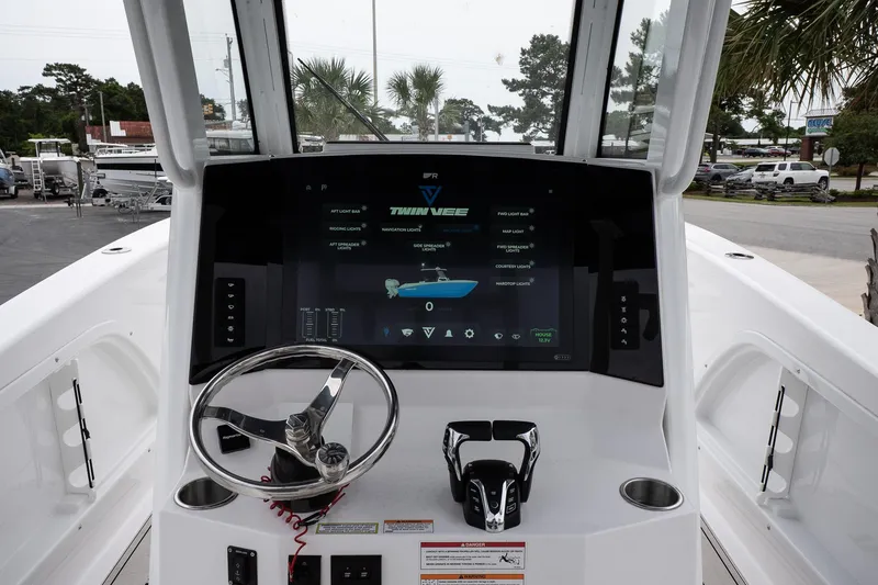 Slide: The Image of 2025 Twin Vee 260 GFX2 CC boat dashboard with steering wheel and digital display. - 28