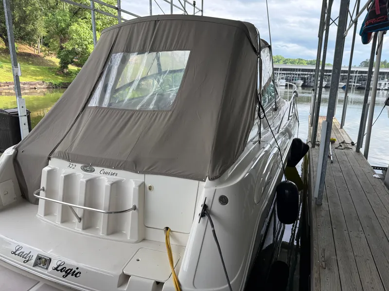 Slide: The Image of 2001 Monterey 322 Cruiser docked, covered with a beige canopy, near a serene waterfront. - 6