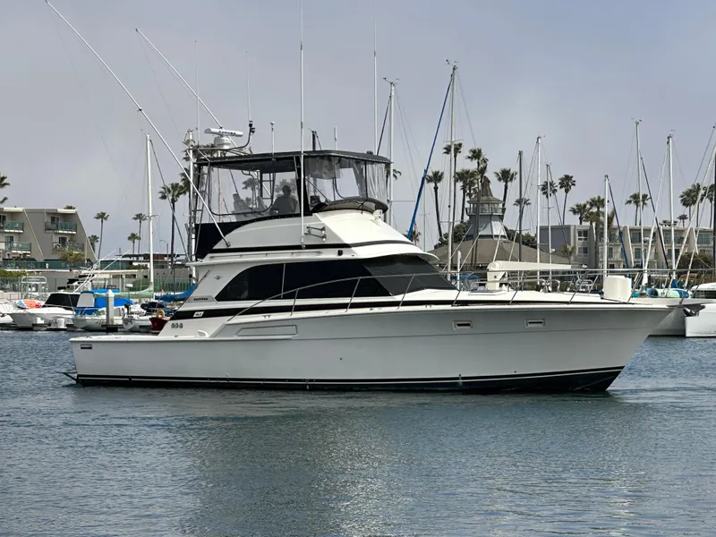 Slide: The Image of 1978 Bertram 46 Convertible yacht docked in a marina, surrounded by sailboats. - 0