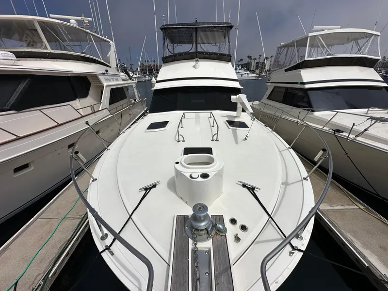 Slide: The Image of 1978 Bertram 46 Convertible yacht docked between two boats in a marina. - 10